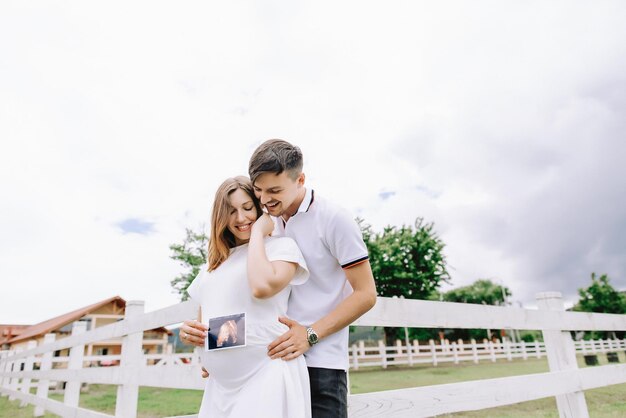 As mãos do homem e da mulher abraçam uma barriga grávida