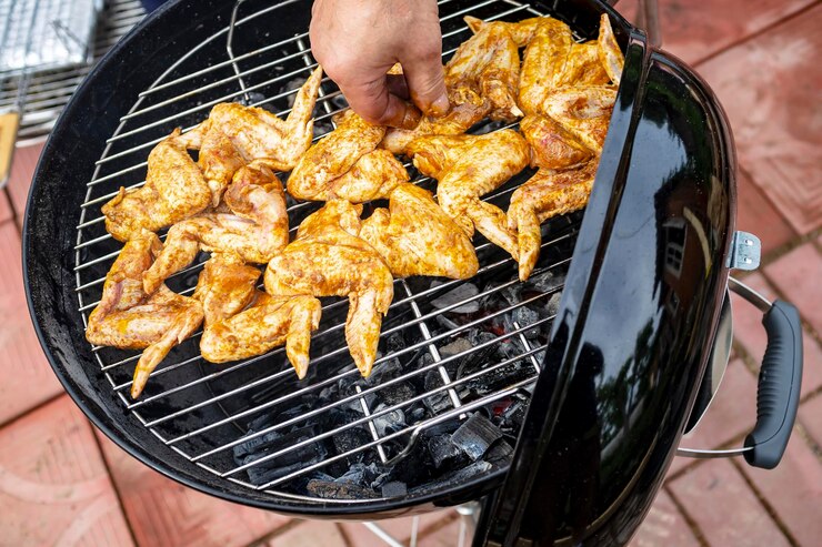 Foto as mãos do homem impõem asas de frango na grelha ao ar livre