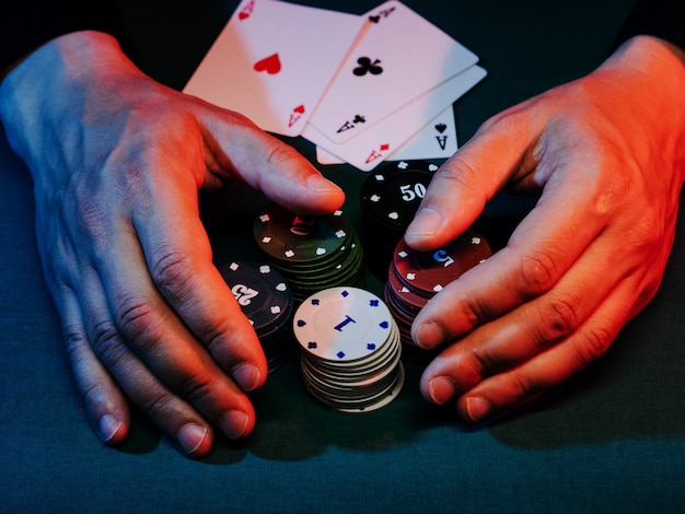As mãos do homem tiram fichas de pôquer