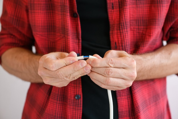 Foto as mãos do mestre eletricista masculino seguram e mostram os cabos dos fios de isolamento conectados para o extensor, detalhes da extensão do filtro de linha durante o reparo.