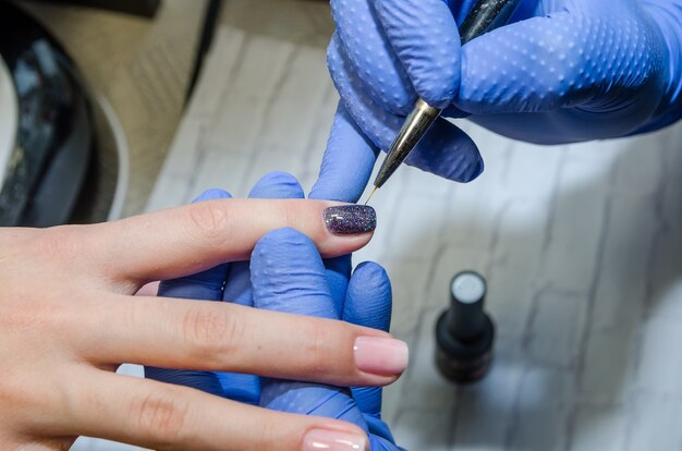 as mãos do mestre pintam as unhas da cliente no salão de beleza