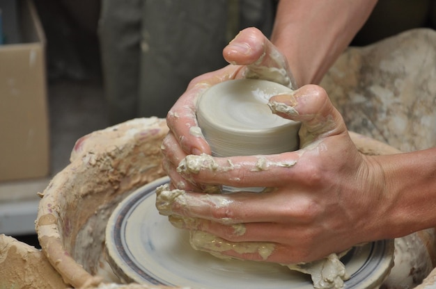 as mãos do oleiro criam um vaso de barro em uma roda de oleiro
