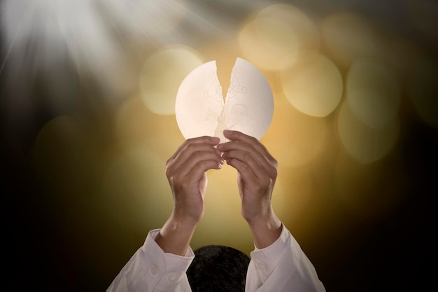 Foto as mãos do pastor dividindo um pão de comunhão brilhante