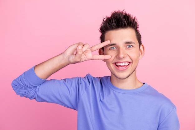 As mãos dos braços do homem da foto mostram vsign perto do olho dizem oi humor animado usando roupa de camisa casual isolada fundo pastel