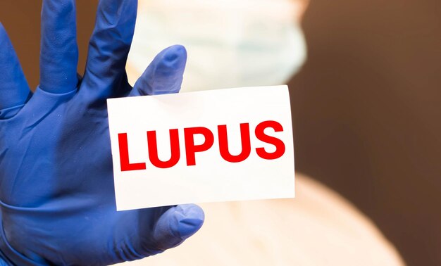 As mãos dos médicos com luvas azuis mostram a palavra lúpus conceito médico