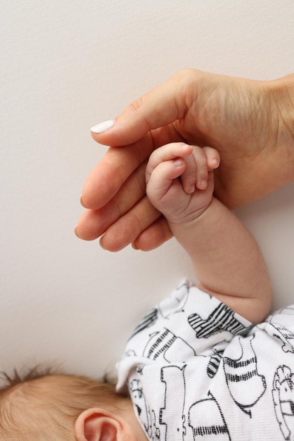 As mãos dos pais seguram os dedos de um bebê recém-nascido A mão de uma mãe e um pai em close-up seguram o punho de um recém-noscido Saúde familiar e cuidados médicos Foto profissional em fundo branco