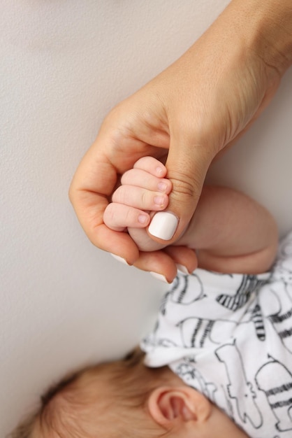 As mãos dos pais seguram os dedos de um bebê recém-nascido A mão de uma mãe e um pai em close-up seguram o punho de um recém-noscido Saúde familiar e cuidados médicos Foto profissional em fundo branco