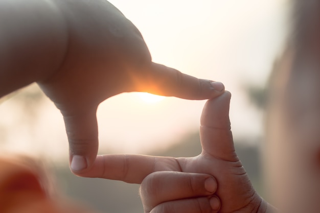 As mãos fazem a forma do quadro ver silhueta bonito fundo do pôr do sol.