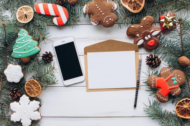 As mãos femininas escrevem um cartão de Natal acolhedor em um fundo de gengivas e presentes.