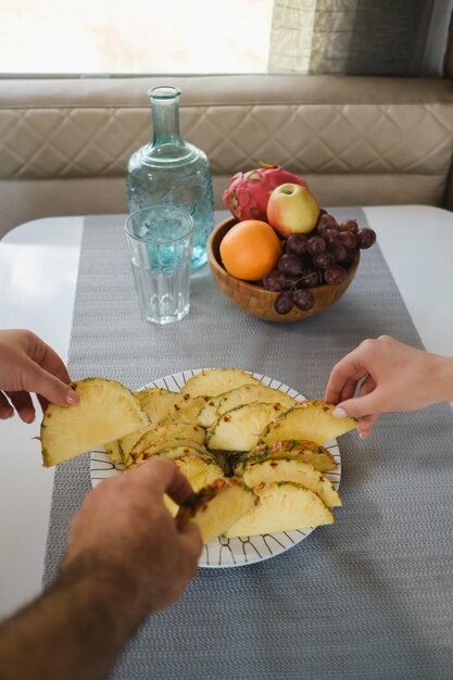 As mãos pegam o abacaxi cortado na mesa do prato