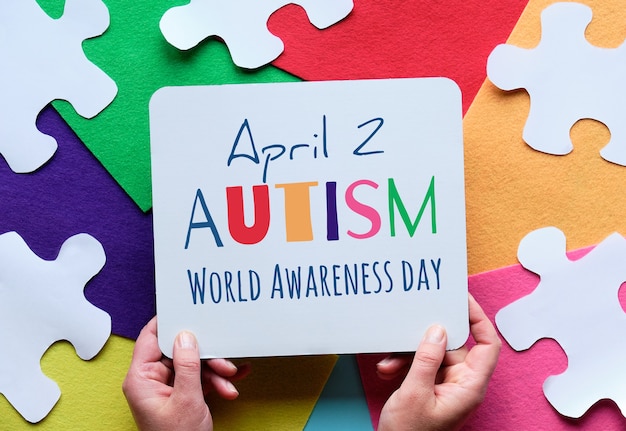 As mãos seguram a prancha com o texto 2 de abril, Dia da Conscientização Mundial do Autismo