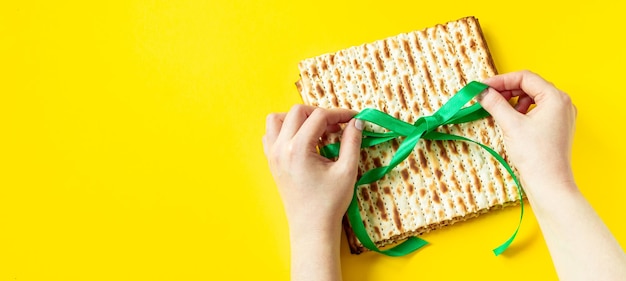 As mãos seguram pão matzo em um fundo amarelo Feliz Páscoa Celebração do feriado religioso judaico Pessach Copiar espaço