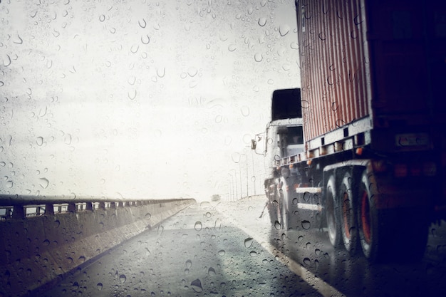 As más condições meteorológicas na estrada durante a tempestade da chuva, veem através do protetor do vento do dia chuvoso. Foco seletivo e cor tonificada.