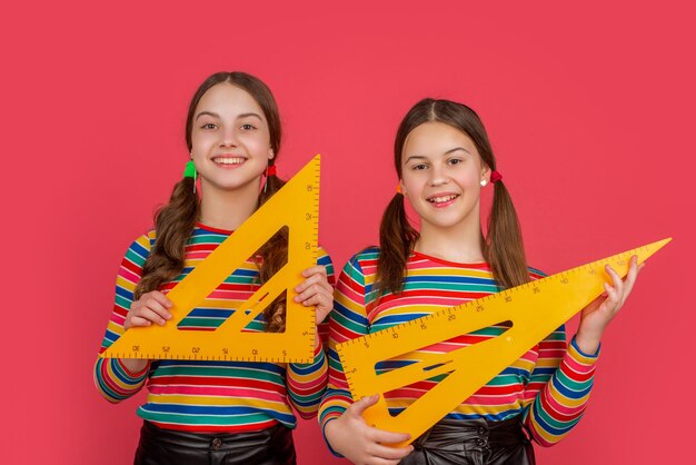 as meninas da escola feliz seguram a ferramenta matemática do triângulo