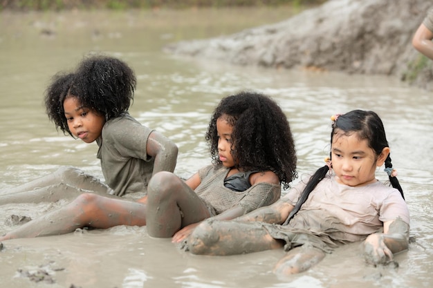 As meninas divertem-se a brincar na lama nos campos da comunidade.