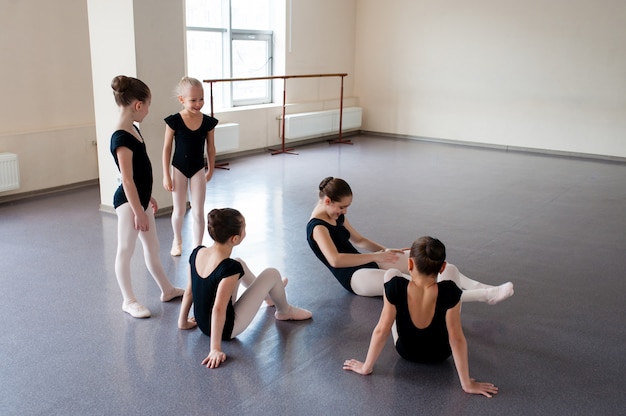 As meninas estão envolvidas em coreografia na aula de balé.