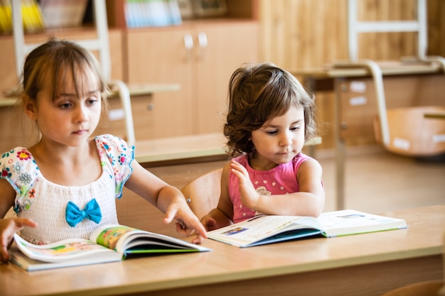 As meninas estão estudando na pré-escola na mesa