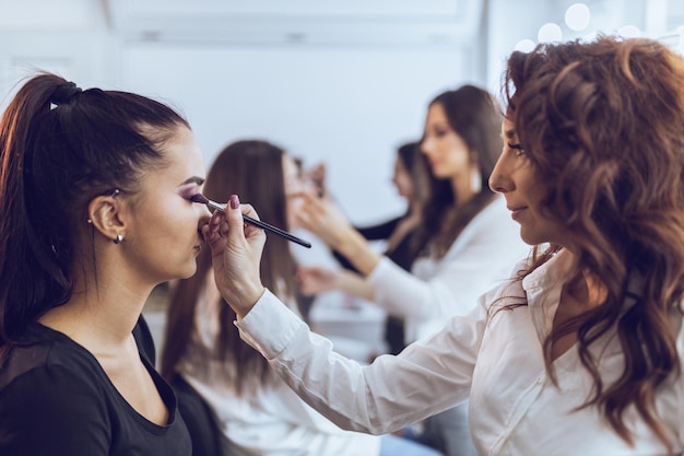 As meninas estão participando da masterclass de maquiagem. Eles estão treinando no modelo como fazer maquiagem perfeita.