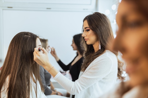 As meninas estão participando da masterclass de maquiagem. Eles estão treinando no modelo como fazer maquiagem perfeita.