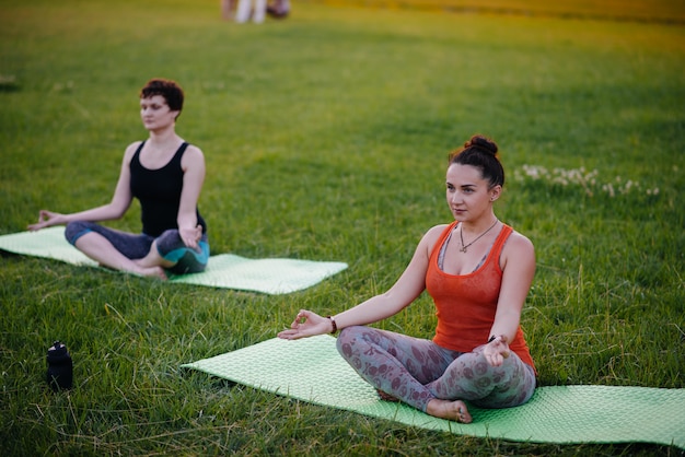 As meninas fazem ioga ao ar livre no parque durante o pôr do sol. estilo de vida saudável.