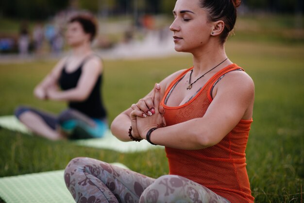 Foto as meninas fazem ioga ao ar livre no parque durante o pôr do sol. estilo de vida saudável