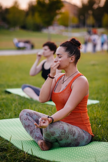 As meninas fazem ioga ao ar livre no parque durante o pôr do sol. Estilo de vida saudável.