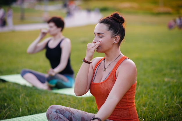 As meninas fazem ioga ao ar livre no parque durante o pôr do sol. Estilo de vida saudável.