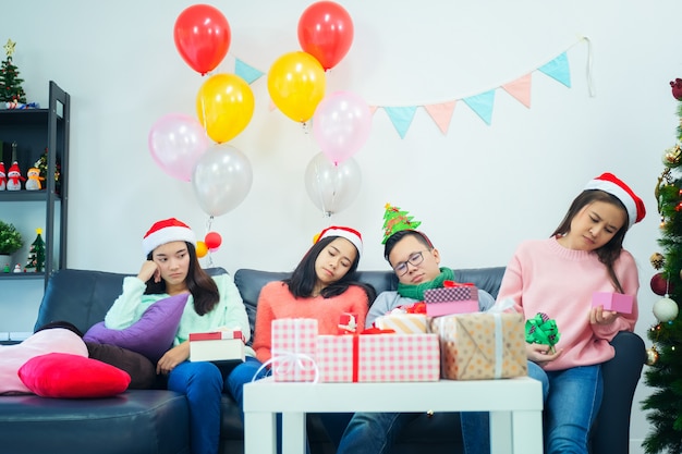 As moças abrem o dia da caixa de presente em casa que sente descontente. rabugentas meninas de chapéu de Papai Noel, comprando roupas de venda de Natal, emoção ciumenta e solitária