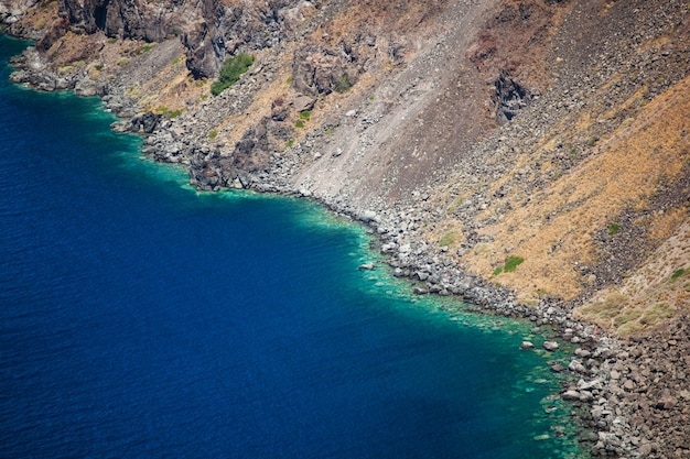 As montanhas e a turquesa vulcânicas molham na ilha de Santorini.