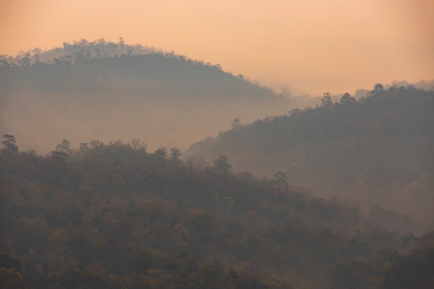 As montanhas estão alinhadas com nevoeiro ao sol da manhã.