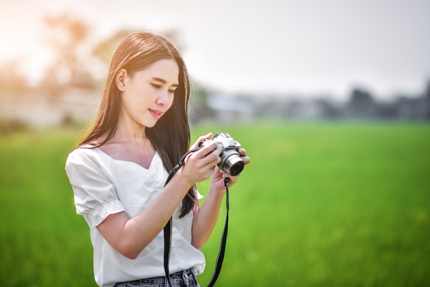 As mulheres asiáticas de beleza segurando a câmera viajam tirar foto em plano de fundo natureza