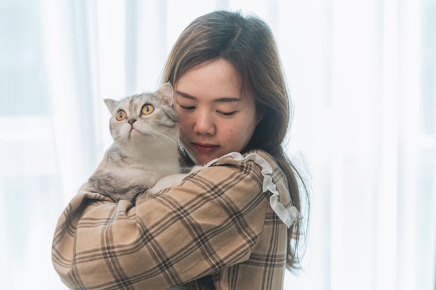 As mulheres asiáticas estão abraçando amorosamente gatos gordos.