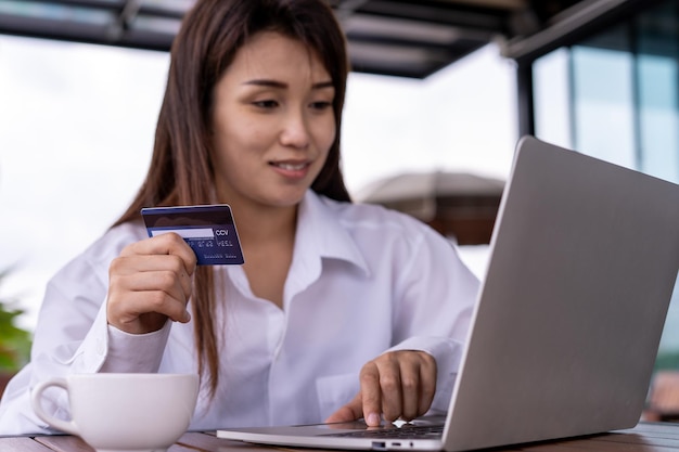 As mulheres asiáticas estão pagando on-line com um código promocional do cartão de desconto de compras Conceito de pagamento de compras on-line