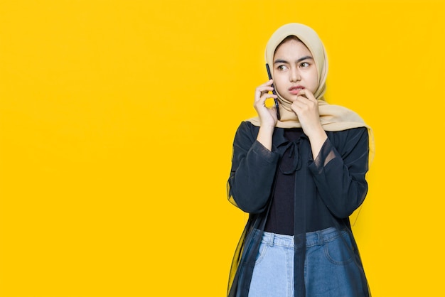 As mulheres asiáticas falam com smartphone na parede amarela