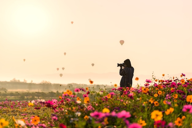 As mulheres de ásia fotografaram a flor e o balão, silhueta do fotógrafo que toma a imagem da paisagem d