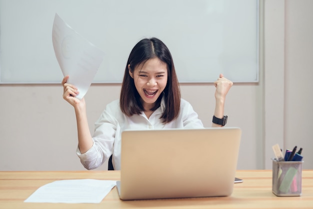 As mulheres de negócios são felizes para ter sucesso no trabalho e mostrar o documento na mesa no backiec back