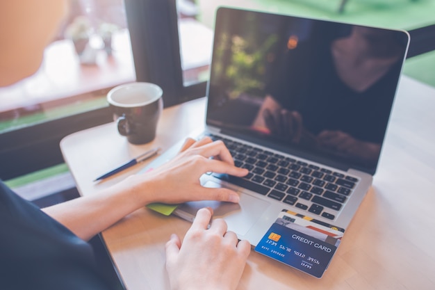 As mulheres de negócios usam cartões de crédito e laptops para fazer compras on-line.