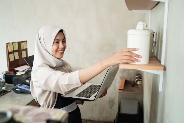 As mulheres do hijab do proprietário do café usam o laptop