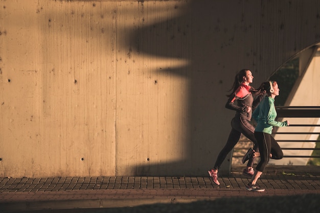 As mulheres jovens que fazem o esporte ao pôr do sol