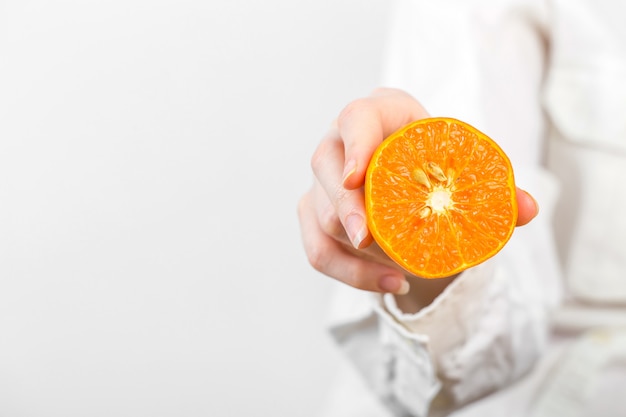 As mulheres mão segurando uma laranja isolada no branco