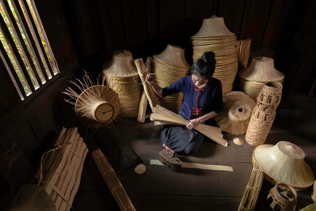 As mulheres novas estão tecendo na cesta handmade do campo de Tailândia.