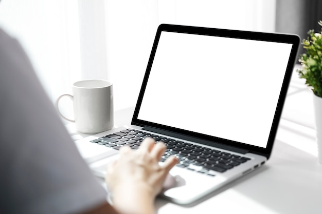 As mulheres que usam o portátil com a tela em branco na tabela no escritório, vista traseira das mulheres de negócios entregam ocupado usando o laptop na mesa de escritório.