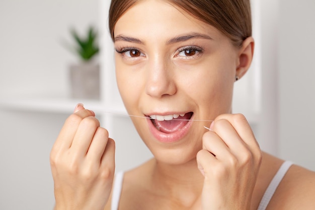 Foto as mulheres sorridentes usam dentes saudáveis ​​de fio dental branco