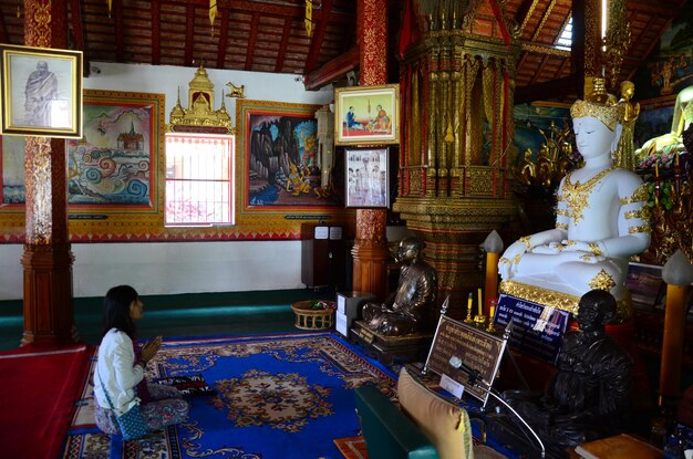 As mulheres tailandesas viajam, visitam, respeitam, rezam, abençoam, desejam mitos, sagrados, místicos, adoram a antiga estátua de Buda de Phra Sing, do templo de Wat Phra Singh, em 24 de fevereiro de 2015 em Chiang Rai, na Tailândia.