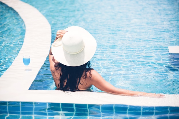 As mulheres usam biquínis e beber cocktails no verão quente na piscina