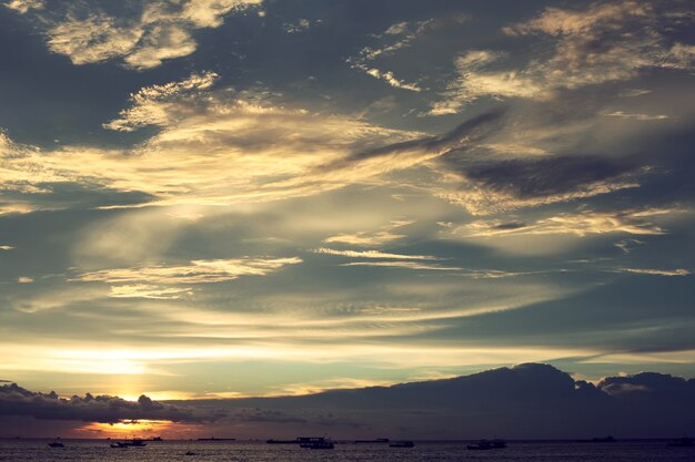 As nuvens do céu do pôr do sol sobre o mar