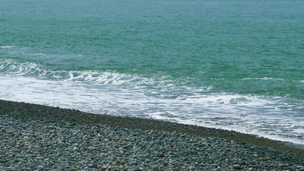 As ondas da água do mar, onda após onda, varrem-se para a costa em movimento lento.