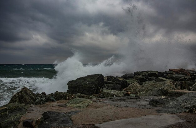 As ondas do mar a salpicar as rochas contra o céu