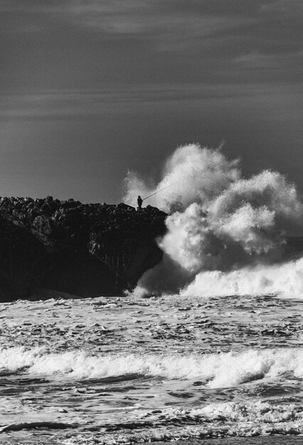 Foto as ondas do mar a salpicar na costa contra o céu