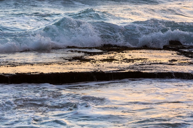 As ondas do mar espirram sobre a plataforma rochosa calma ao amanhecer